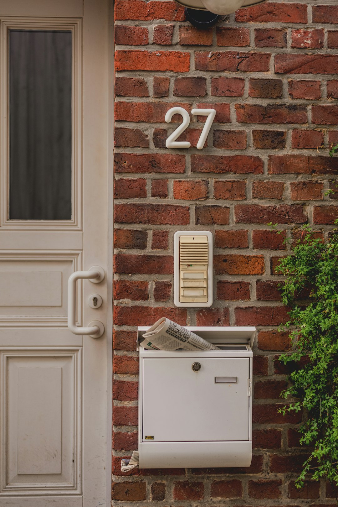 White mailbox with newspaper on brick wall delivery package, payment card, home address