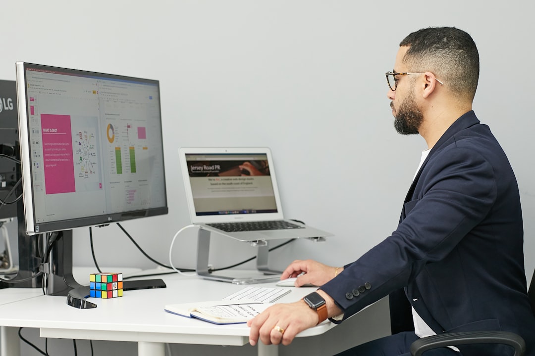 a man sitting at a desk with a laptop and a computer rpa dashboard, automation workflow, office software