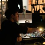 A person adjusting controls on a sound mixing board. event control room, production team, live show cues