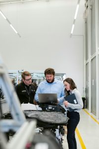 group of people sitting on chair in front of table with laptop computers engineering team, product lifecycle, digital workflow