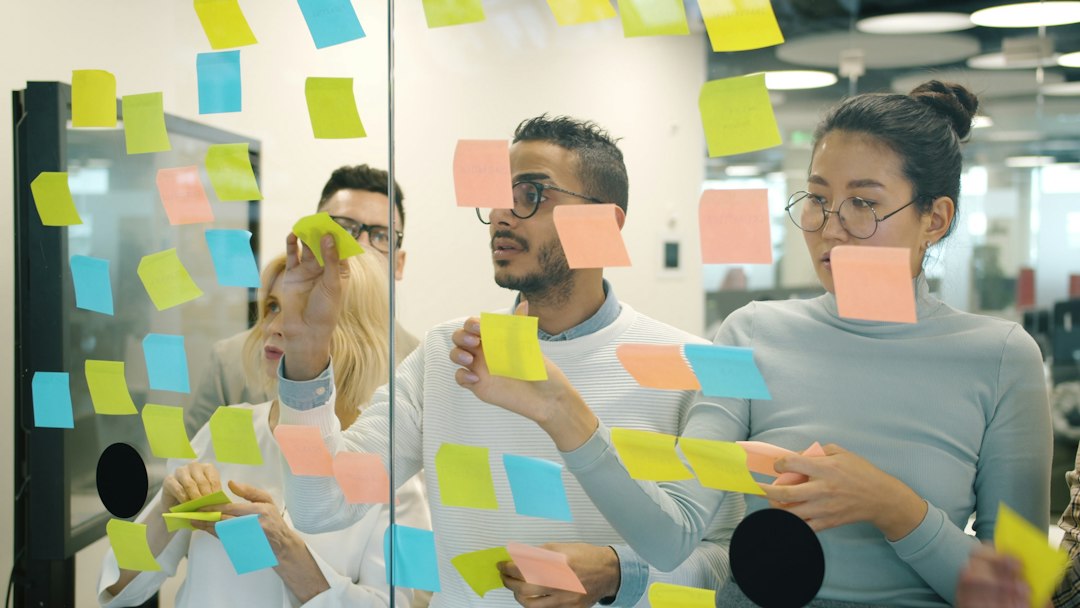 Team brainstorming ideas on a glass wall with sticky notes team voting, whiteboard, name ideas, happy coworkers