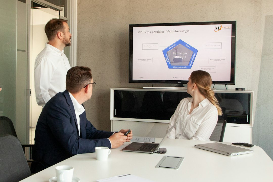 Three people in a meeting room looking at a presentation crm dashboard, email performance, customer journey