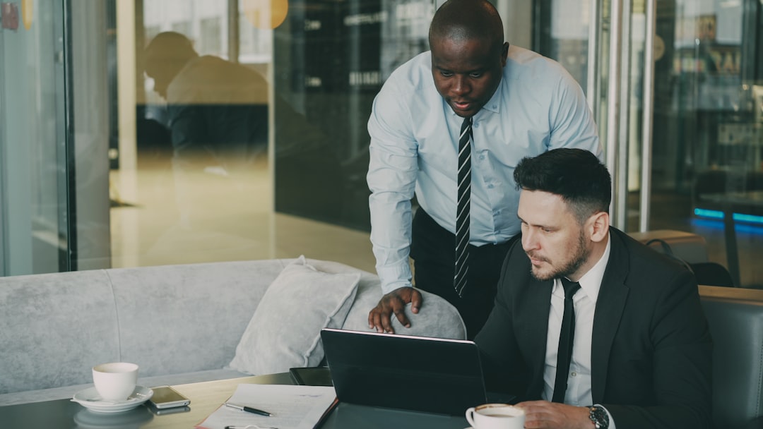 Two businessmen collaborating over a laptop. payroll software, employee benefits, small business hr