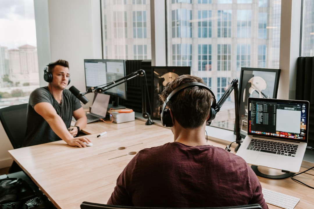 two men sitting by the table using microphone and headphones inside studio during daytime podcast analytics, reply rates, outreach results