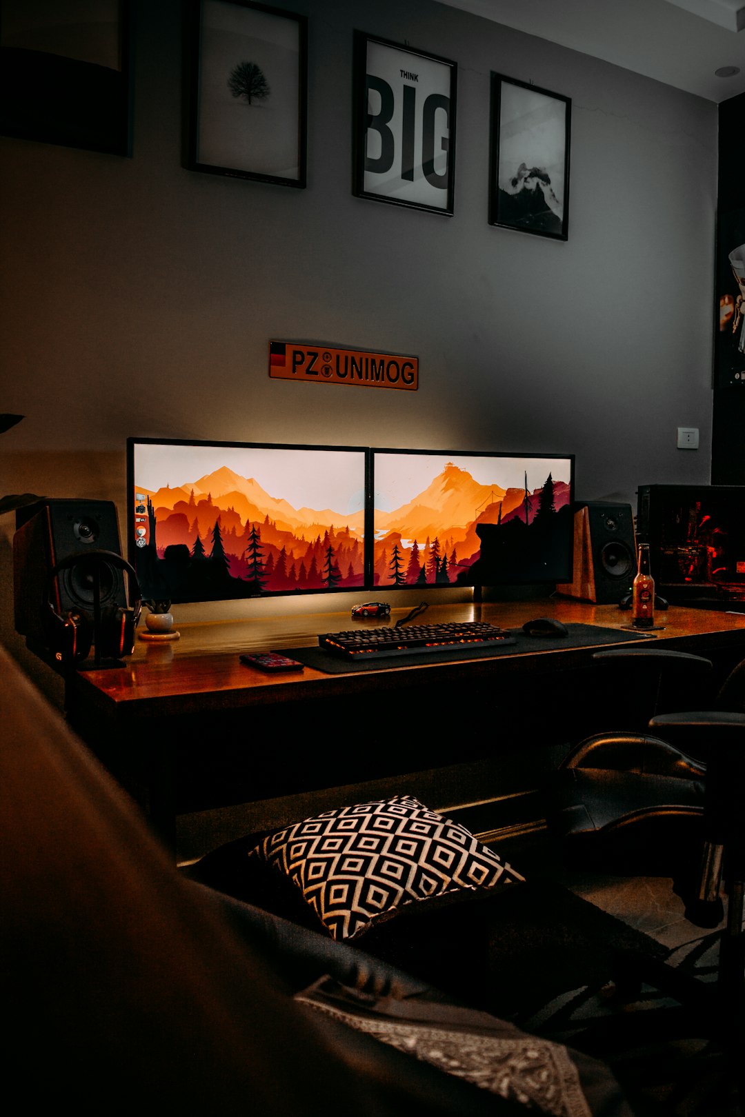A dual monitor setup with a mountain landscape wallpaper on a wooden desk gaming setup, launch night, open world game