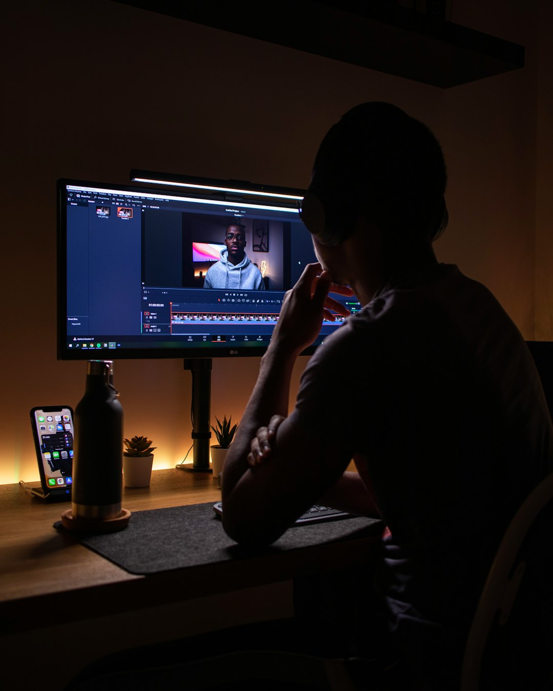 A person wearing headphones editing video on a computer in a dark workspace video editing tools, creator workflow, social media content