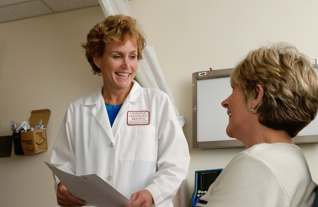 A smiling doctor in a white coat talking to a patient in a clinic patient visit, ambient recording, clinical notes
