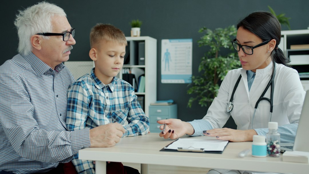 Doctor consults with grandfather and grandson in office behavior therapist tablet, child session, progress chart, clinic
