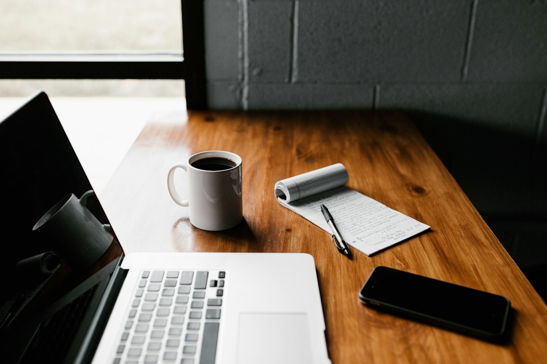 MacBook Pro, white ceramic mug,and black smartphone on table business client, email reply, office desk