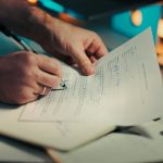 Man signing a document with a pen sole proprietor, limited liability company, business paperwork