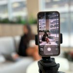 Smartphone recording a woman on a couch instagram reel analytics, watch time, shares, saves
