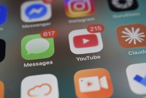 Smartphone screen showing app icons with red notification badges for Messages and YouTube video sharing apps, cloud upload, compressed video