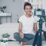 Young woman filming herself with a camera creator planning reel, content checklist, phone tripod
