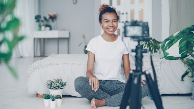 Young woman filming herself with a camera creator planning reel, content checklist, phone tripod