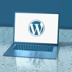 A blue laptop displaying the WordPress logo on a speckled blue surface wordpress error screen, bug icon, magnifying glass