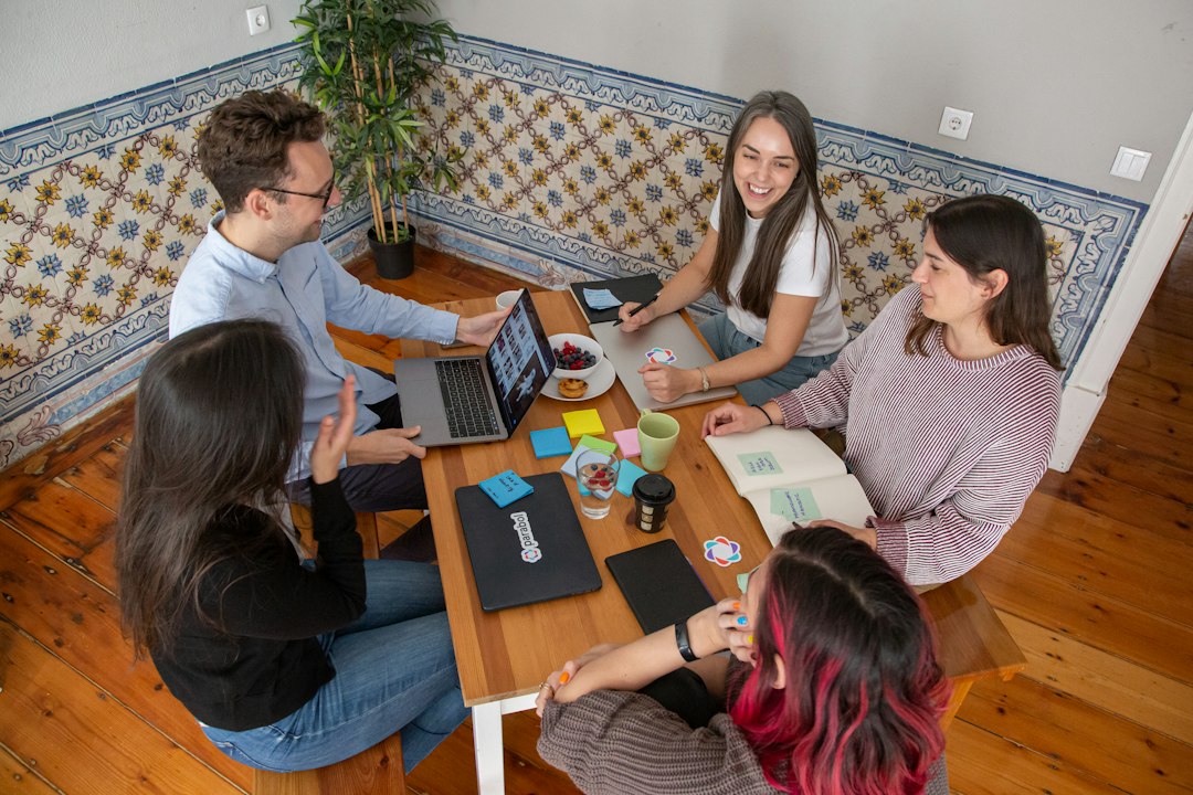 a group of people sitting around a wooden table shared document editing, comments, suggestions, remote team