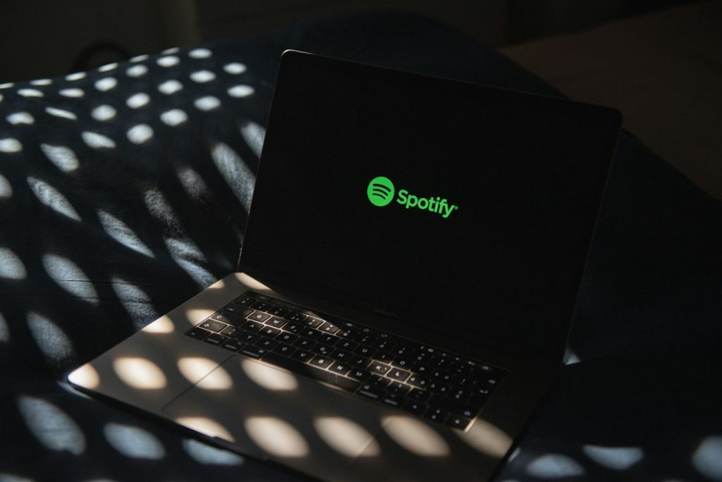 a laptop computer sitting on top of a bed musician laptop spotify upload
