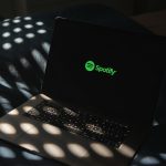 a laptop computer sitting on top of a bed musician laptop spotify upload