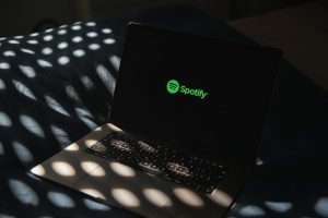 a laptop computer sitting on top of a bed musician laptop spotify upload