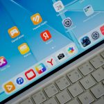 A tablet screen displaying various app icons above a white keyboard music apps comparison, streaming services, desktop icons