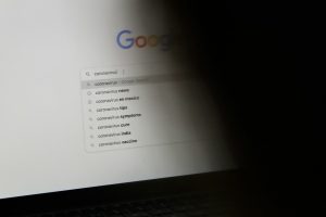 black laptop computer turned on displaying google search google docs toolbar, text formatting, strikethrough menu
