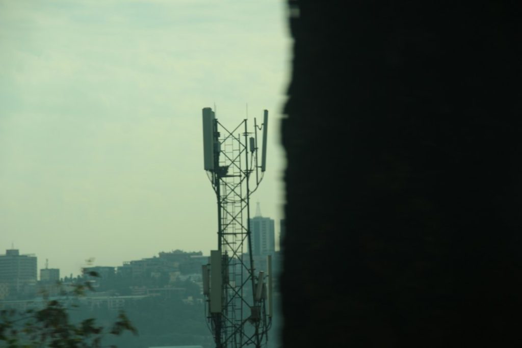 Cell tower against a hazy cityscape background smartphones, coverage map, city towers
