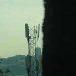 Cell tower against a hazy cityscape background smartphones, coverage map, city towers