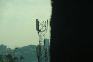 Cell tower against a hazy cityscape background smartphones, coverage map, city towers