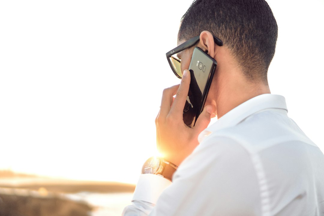 man holding smartphone standing in front of calm body of water customer support, prepaid card, phone call, balance issue