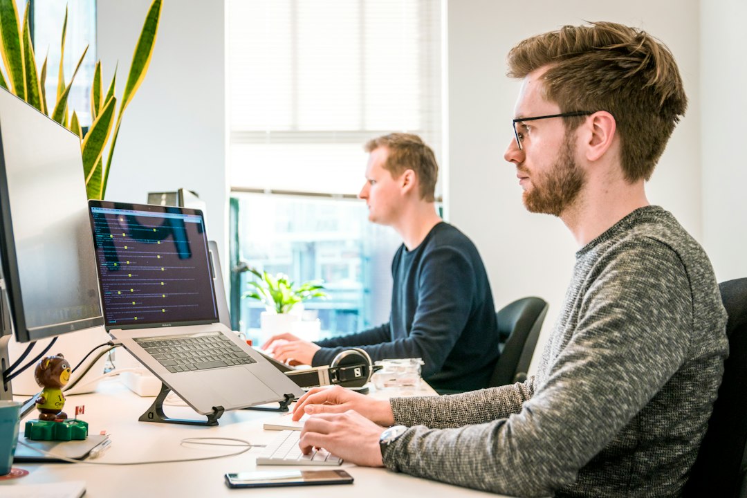 man sitting on chair wearing gray crew-neck long-sleeved shirt using Apple Magic Keyboard web development team code review