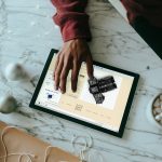 Overhead view of a person clicking on a Surface laptop with wrapping presents around online store builder, product grid, checkout screen