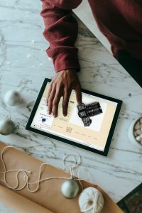 Overhead view of a person clicking on a Surface laptop with wrapping presents around online store builder, product grid, checkout screen
