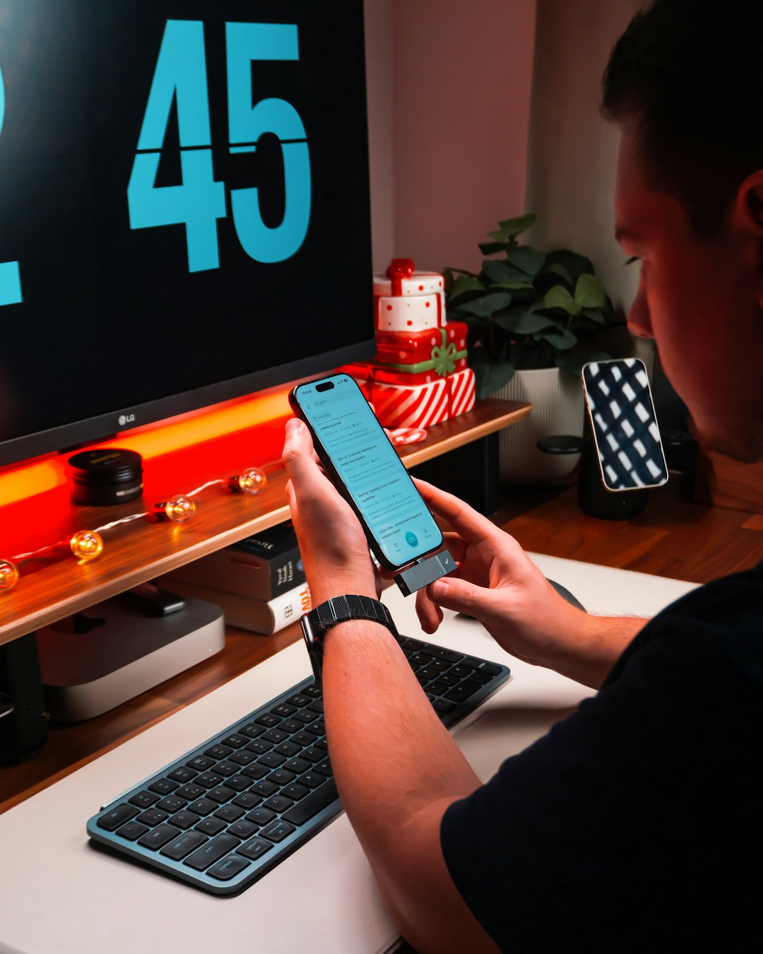 Person holding smartphone at desk with computer phone speed test, signal bars, home office